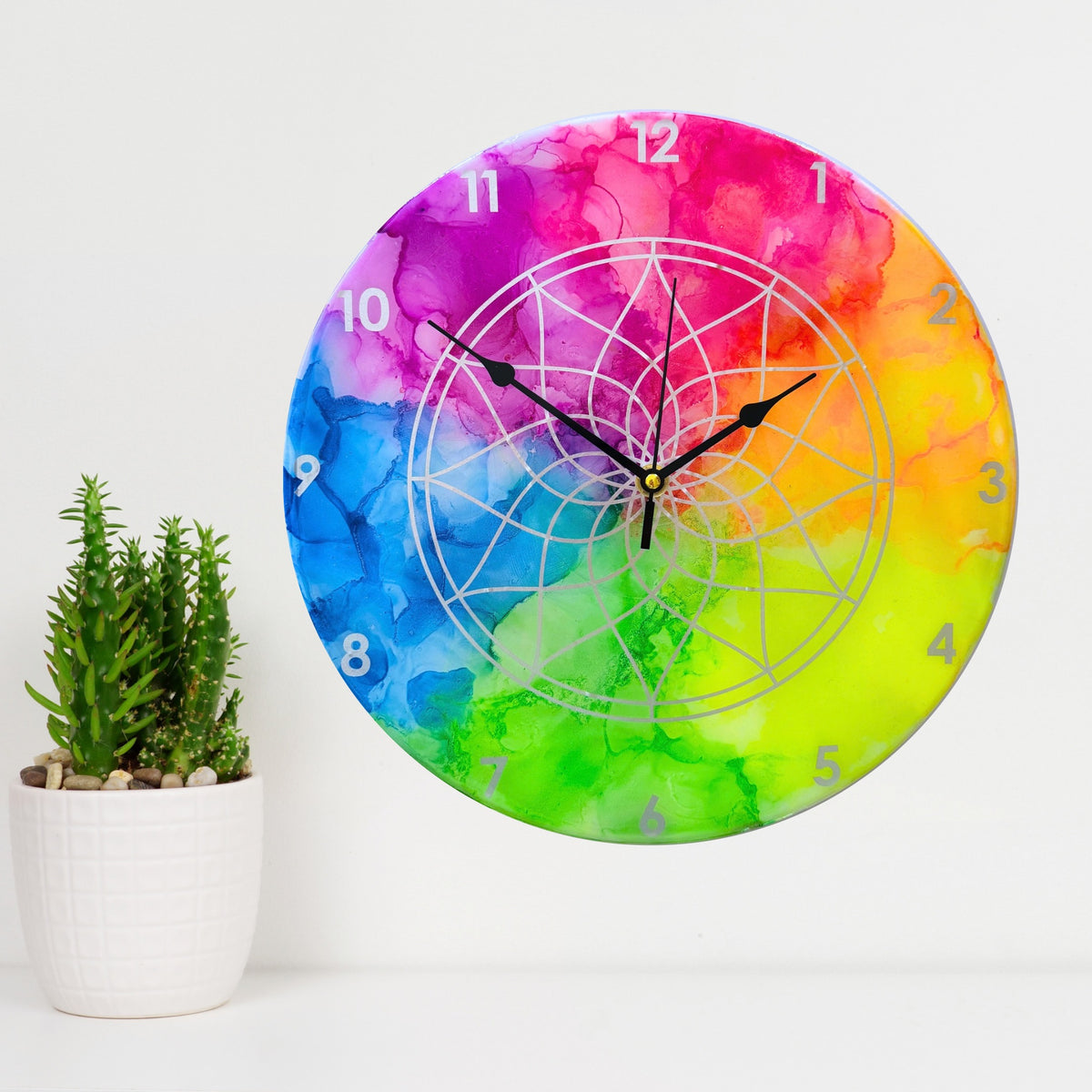 A neon coloured clock with silver detail and black hands