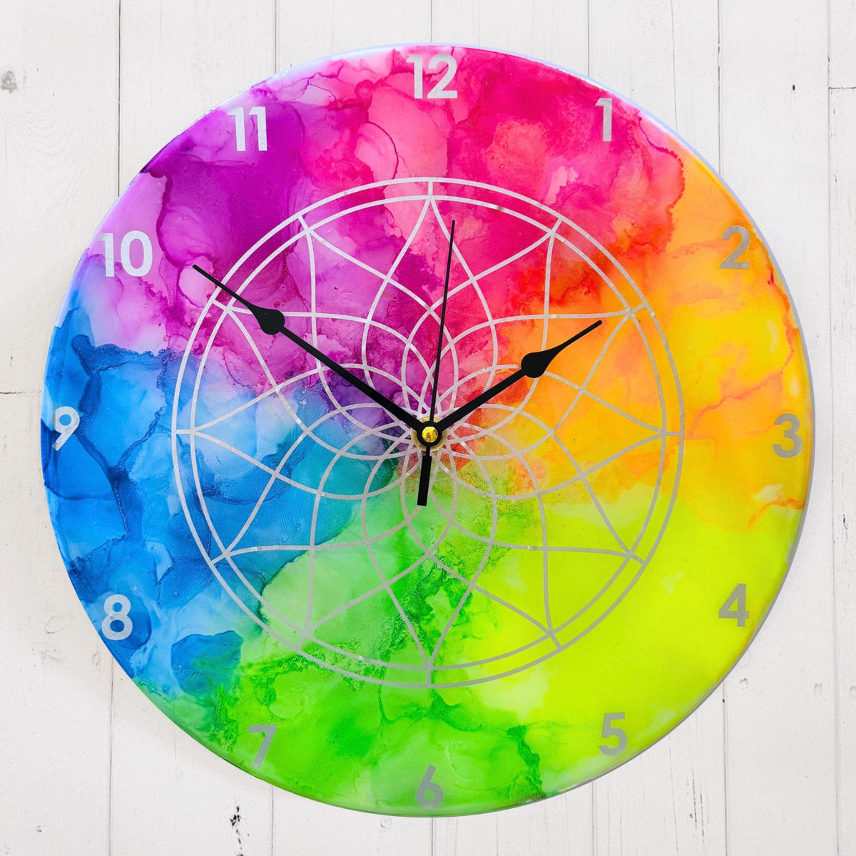 A neon coloured clock with silver detail and black hands