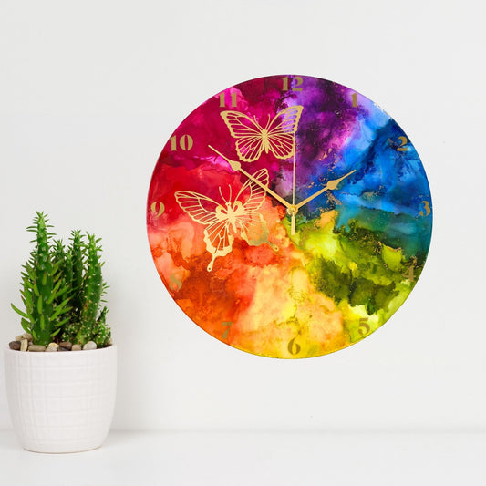 Round wall clock with a vibrant rainbow design and gold butterfly illustrations, with gold arabic numerals and gold hands.