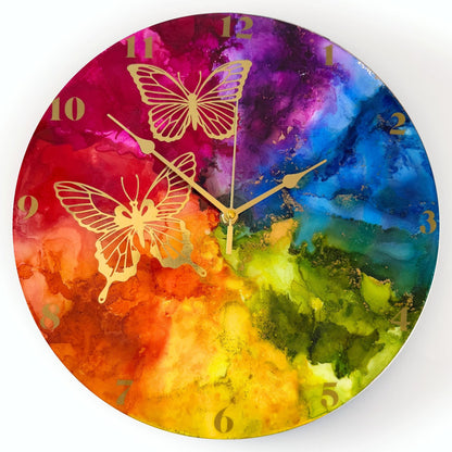Round wall clock with a vibrant rainbow design and gold butterfly illustrations, with gold arabic numerals and gold hands.