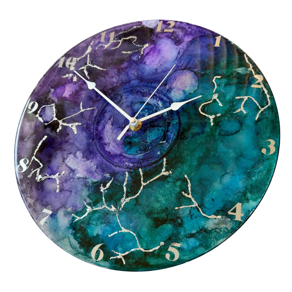 Round wall clock with a watercolour-style marbled face in purple, teal, and blue, with silver clock hands and silver Arabic numerals.