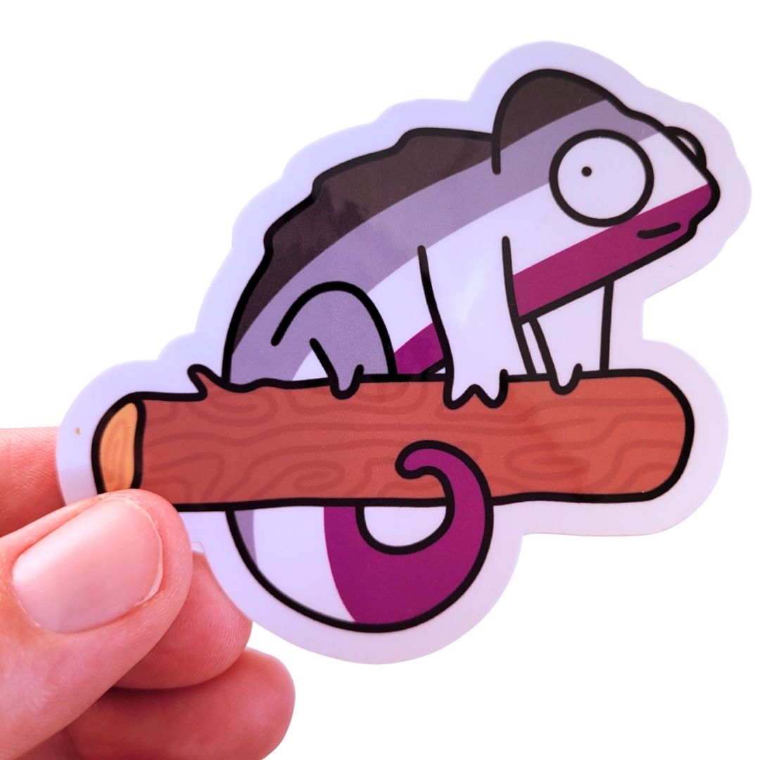 Sticker of an asexual flag chameleon on a branch held by a hand against a white background