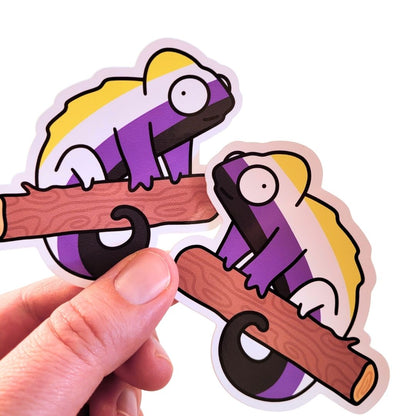 Two sticker design of a non-binary chameleon on a branch held by a hand against a white background
