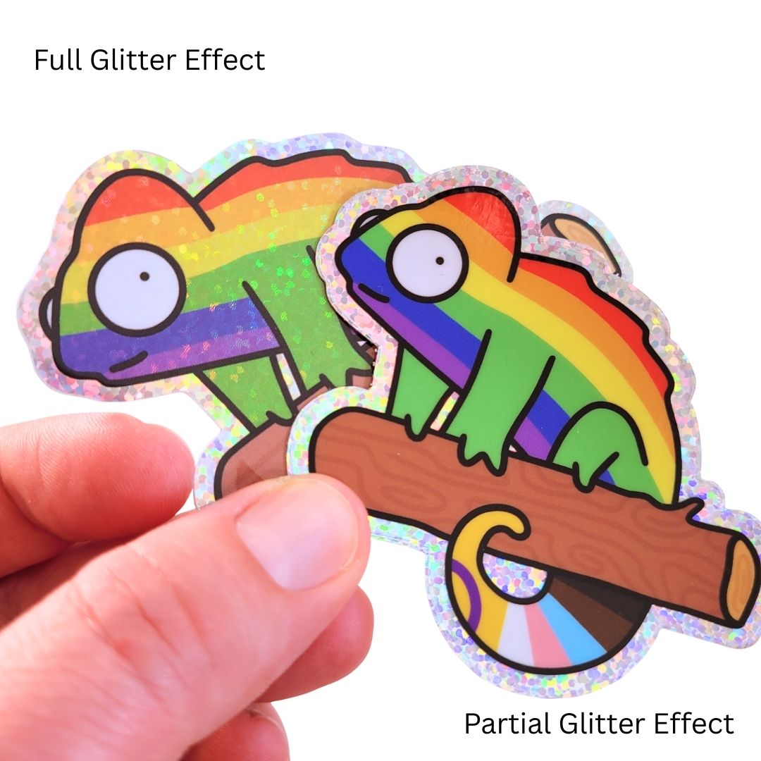 Hand holding two colorful stickers with a chameleon on a branch, showing full and partial glitter effects.