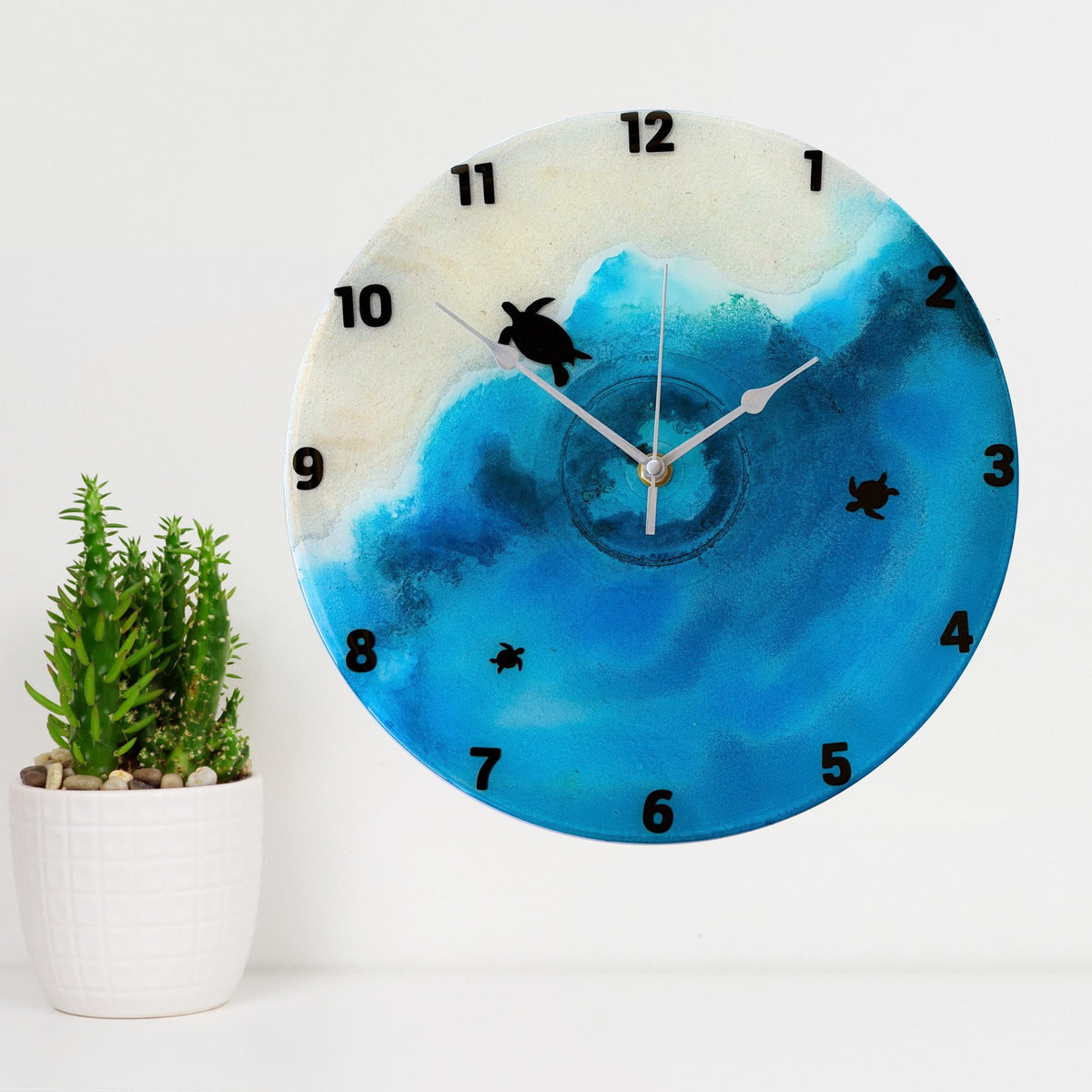 A beach coloured clock with black numbers and turtles