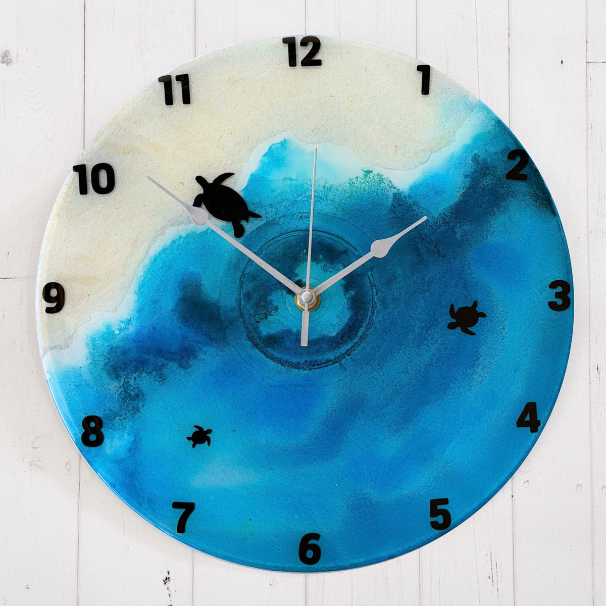 A beach coloured clock with black numbers and turtles