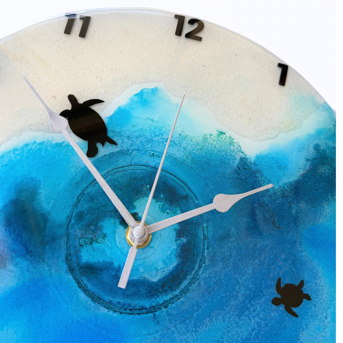 A beach coloured clock with black numbers and turtles